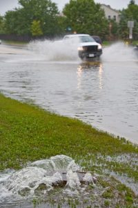 Photo shows a pickup truck driving through a flooded street.