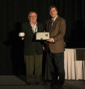 Two men, one handing the other an award. Paul Andre Bolduc is the recipient of a CMOS volunteer award