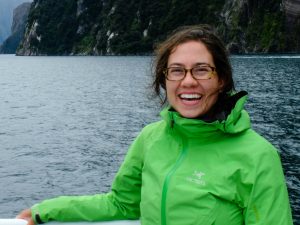 Photograph of Tara Howatt, Ocean Gliders to Study Baleen Whale Habitat in Roseway Basin. She is a young woman with dark hair and glasses, standing on a boat with a rockface in the background.