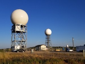 Photograph showing 2 radar towers against a blue sky
