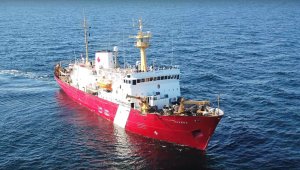 white and red research vessel facing you, on the ocean
