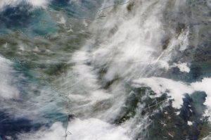 satellite image of land and sea, and white whispy contrails