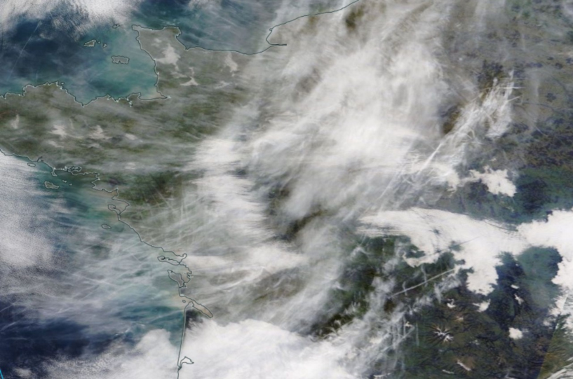 satellite image of land and sea, and white whispy contrails